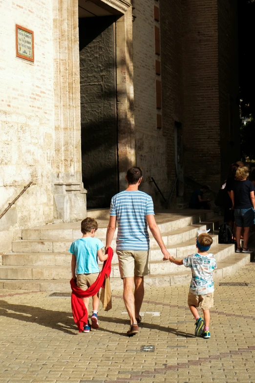 a man is holding hands with two small children