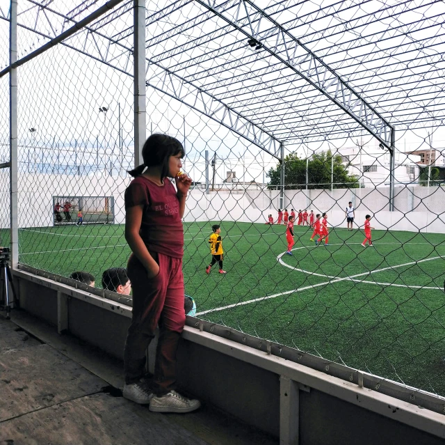 the girl stands on a bench in front of the soccer field