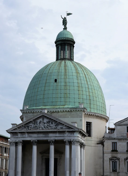 a large domed building with pillars and a statue at the top