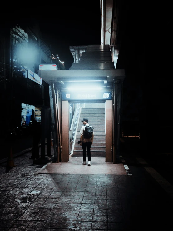 a man stands outside at night next to the steps