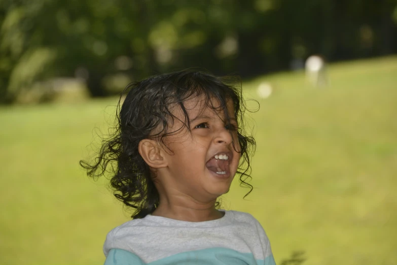 a child is laughing as sheep stand on the grass in the background