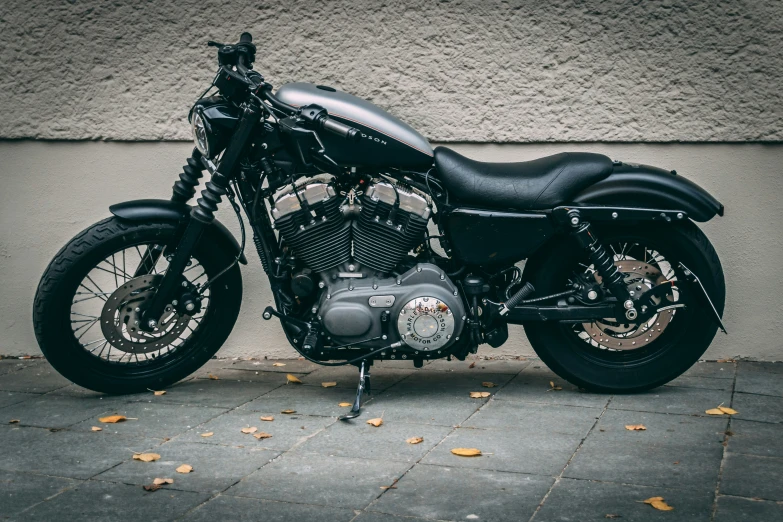 a black motorcycle sits parked on a gray sidewalk