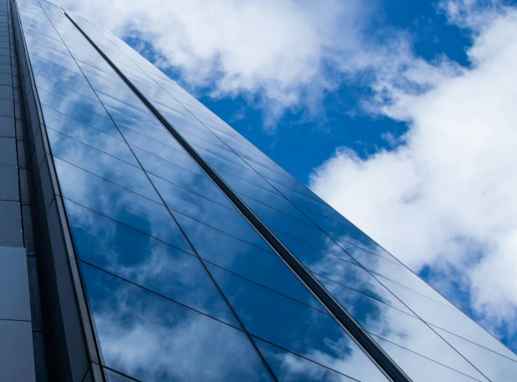 a blue glass skyscr under a partly cloudy sky