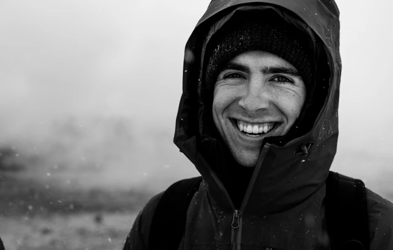 a smiling man in black and white standing on a mountain