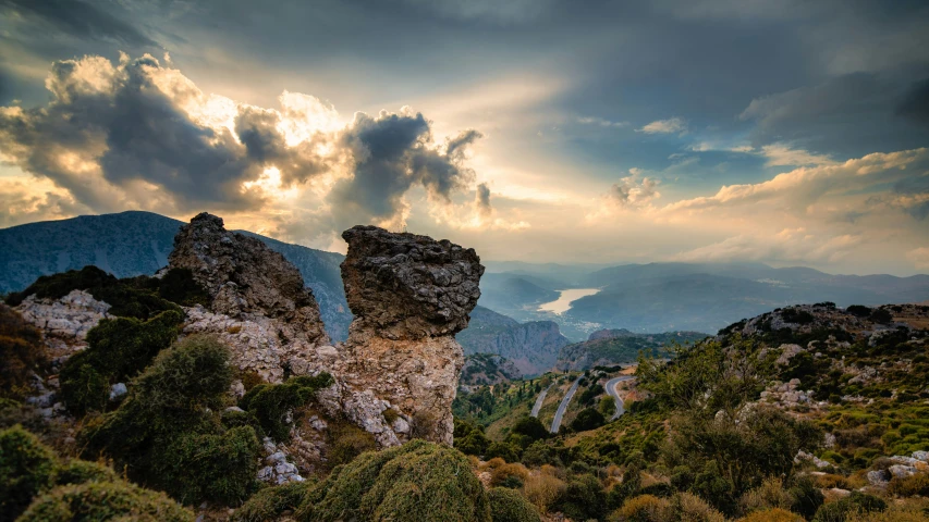 large rocks surrounded by trees and greenery under a cloudy sky