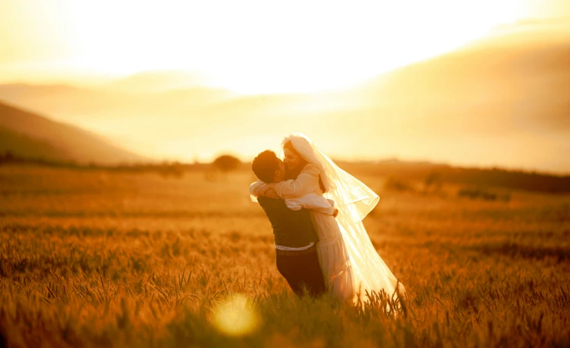 a couple hugging each other in a field of tall grass