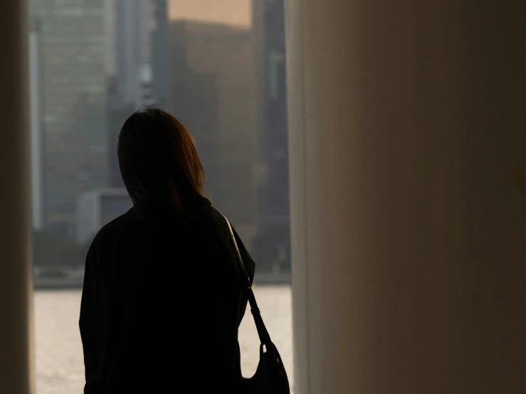 a woman standing next to the water while looking out the window