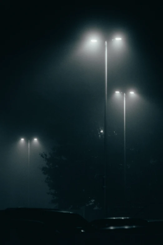 some street lights a car some fog and trees