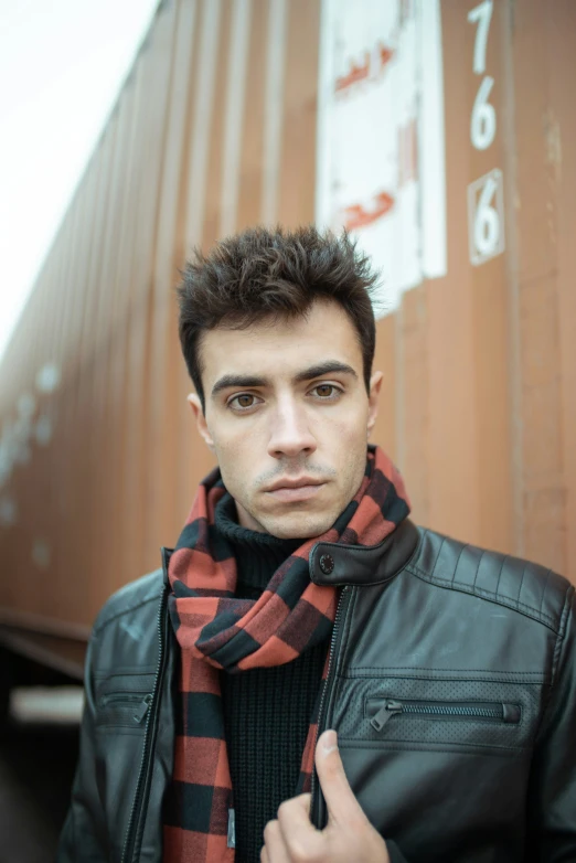 a man wearing a scarf is standing next to a train