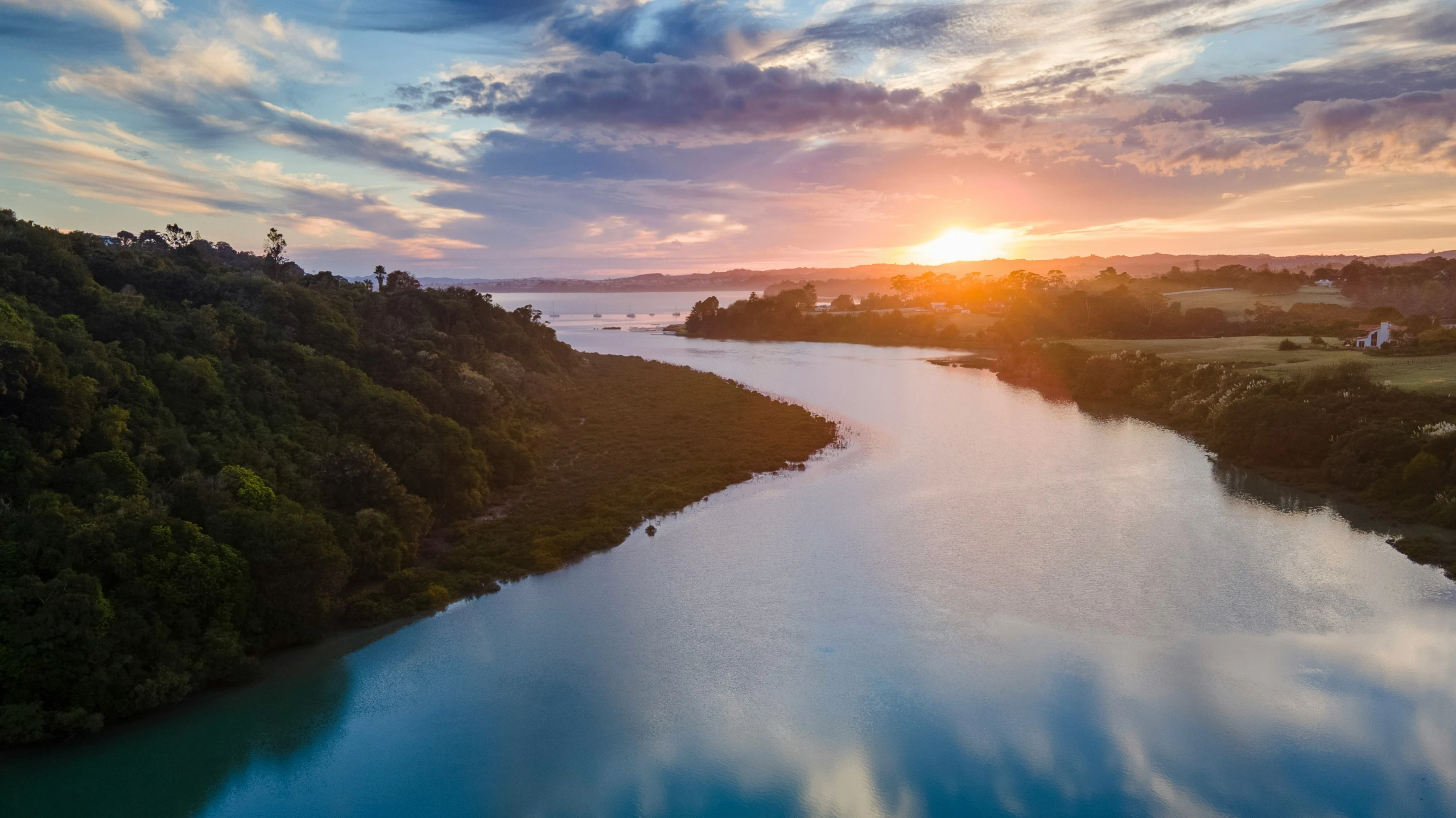 a sun setting over a river with a beautiful sky