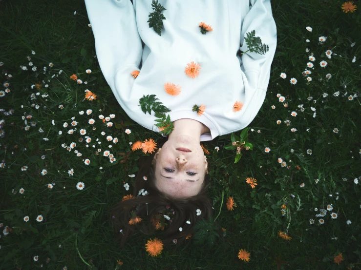 a girl laying in grass with flowers all around