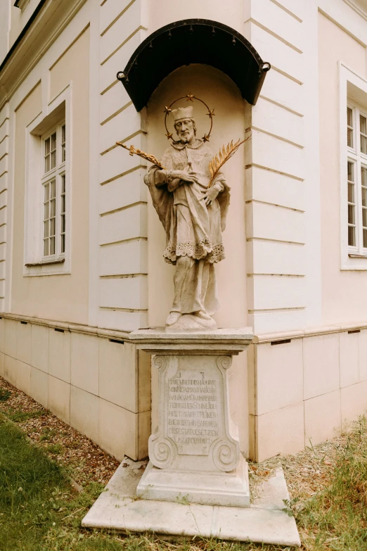 a statue in front of a building with windows and grass