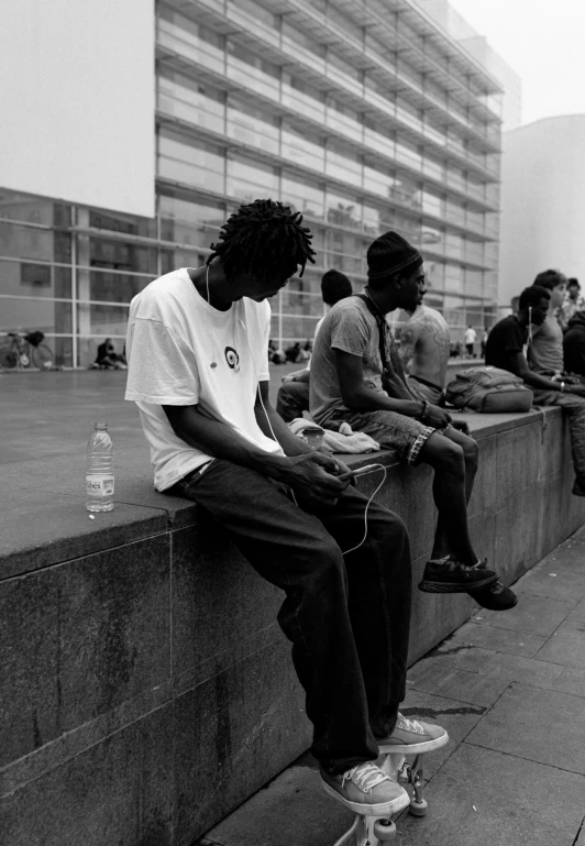 people sitting along the wall in a parking lot