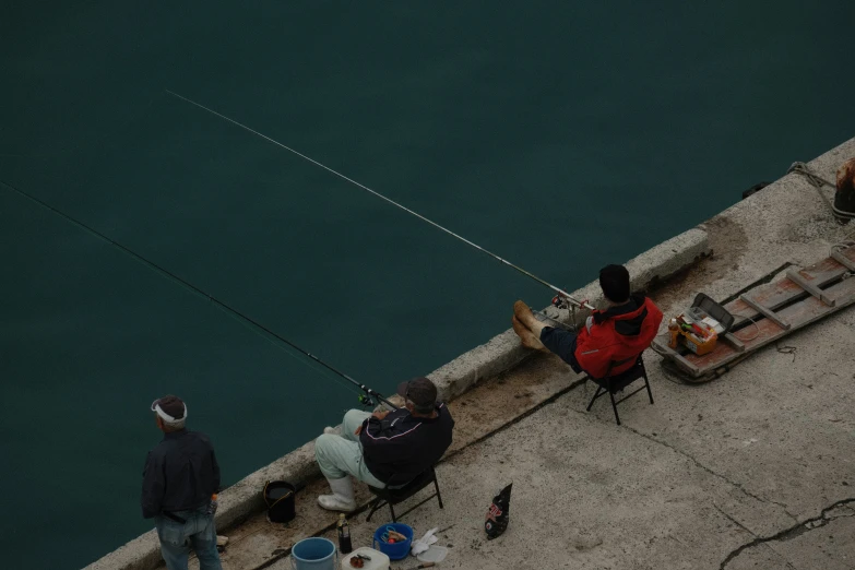 people sitting on a bench near the water while fishing