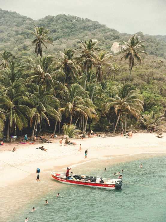 a beach area with a boat on it and people walking around