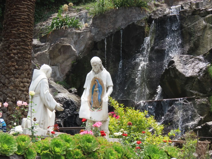 a statue of two men with white hair standing in front of water fall