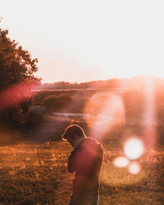 the boy is staring up at the sun in the distance