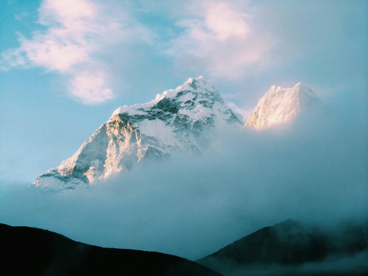 the top of a mountain in clouds at dusk