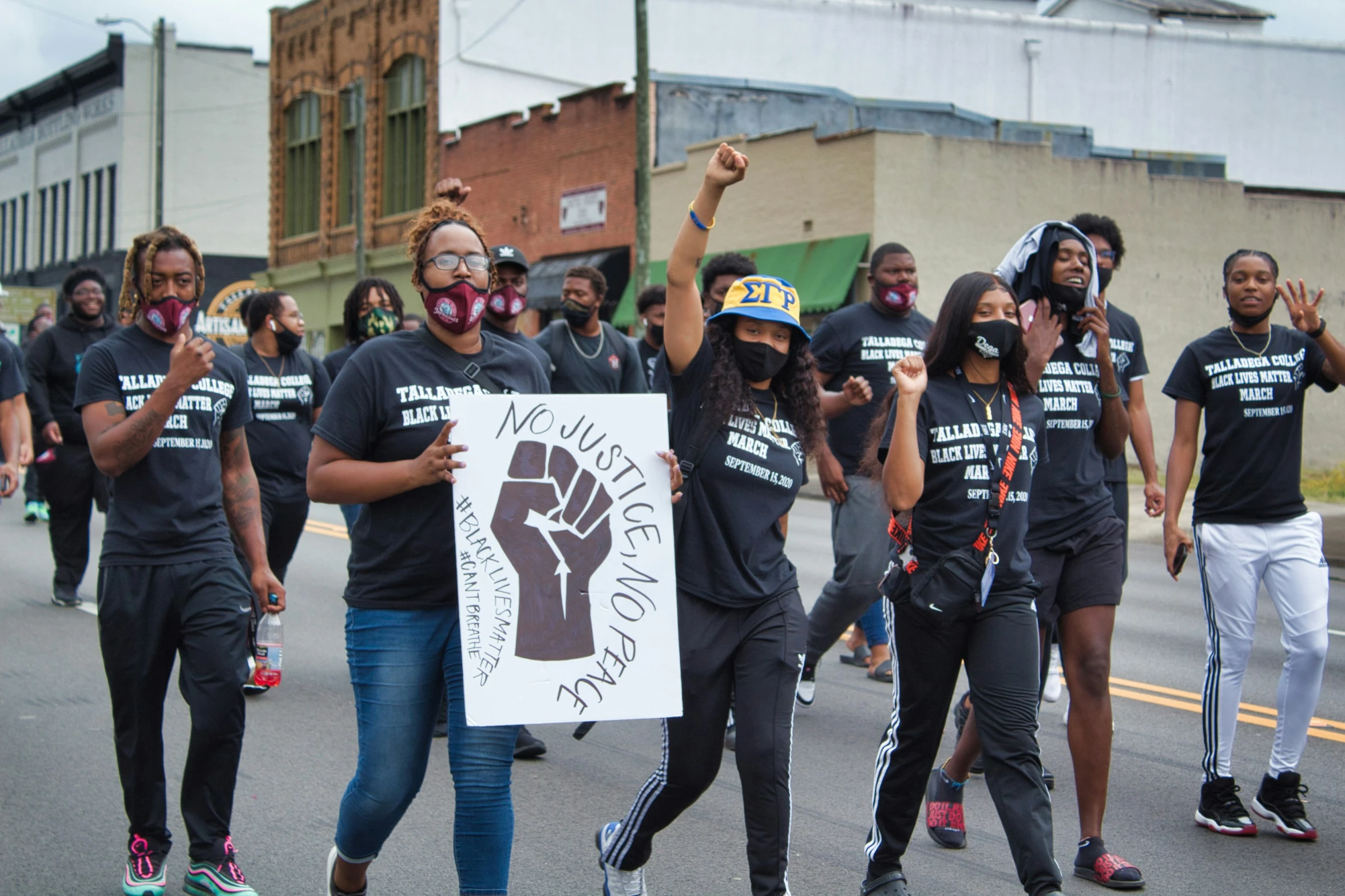 a group of people standing in the street, one woman is holding a sign