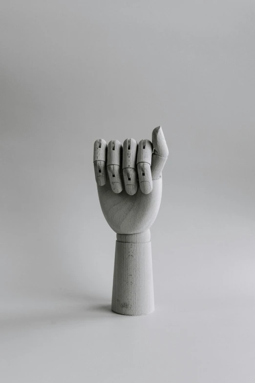 a small, white plastic hand statue sitting in front of a white background