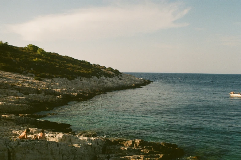 a lone boat sits on the waters edge near some cliffs