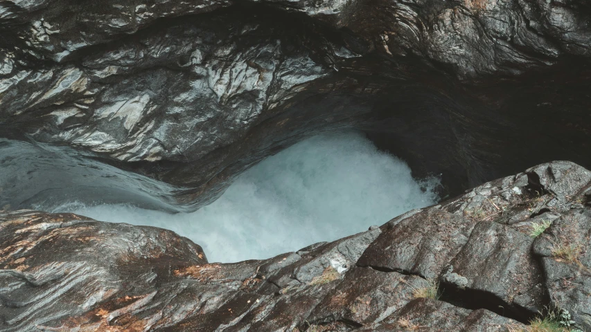 a lake surrounded by large rocks with small waterfall