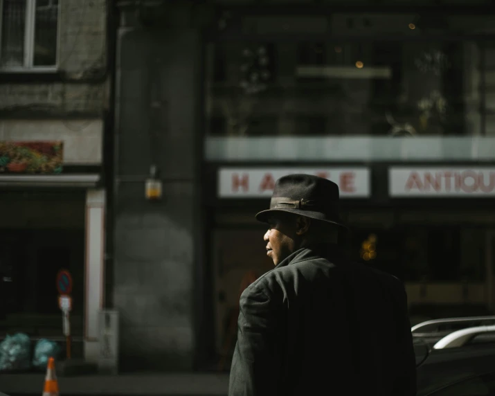 a man wearing a hat standing next to a building