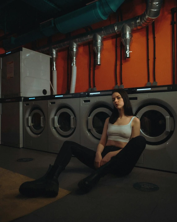 a young woman sitting on the floor of a laundry machine