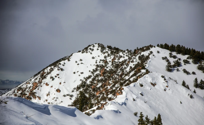 an almost barren snow covered mountain on a cloudy day