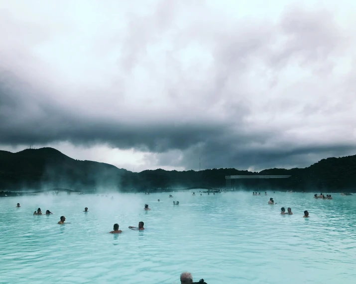 people swim in blue lagoon in the middle of the forest
