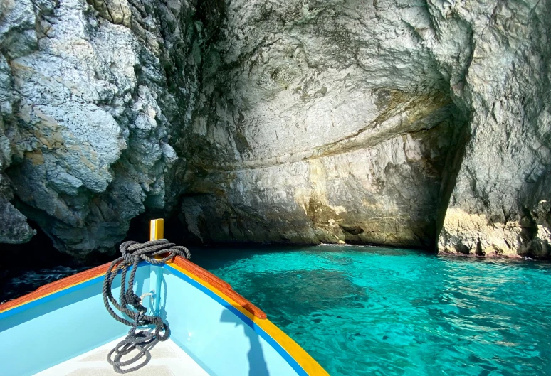 a blue boat in the water next to rocks