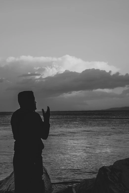 person standing near a body of water flying a kite