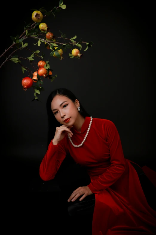 a woman with a red dress and pearl necklace sitting down