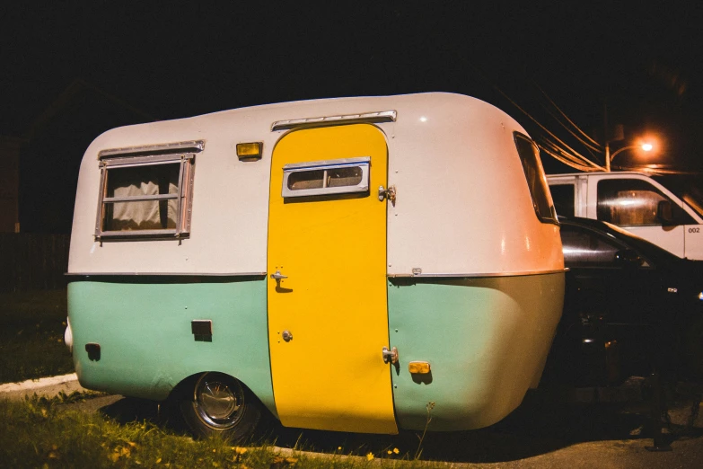 an old school trailer parked near a white car