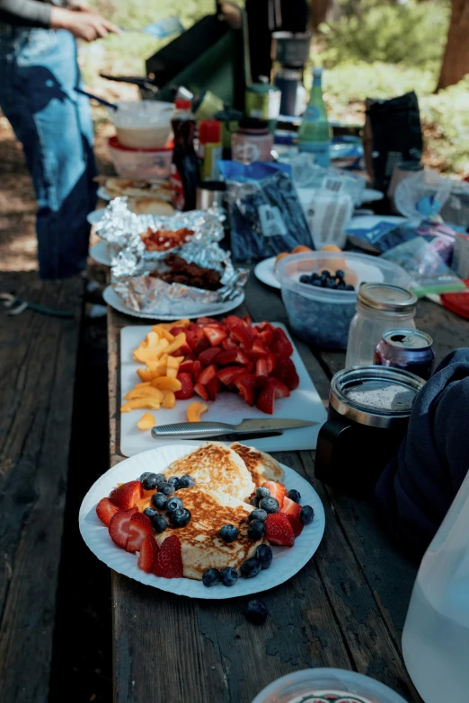 a couple plates full of fruit and a bagel with a side of french toast