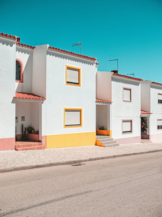 a white building with yellow trim next to a street