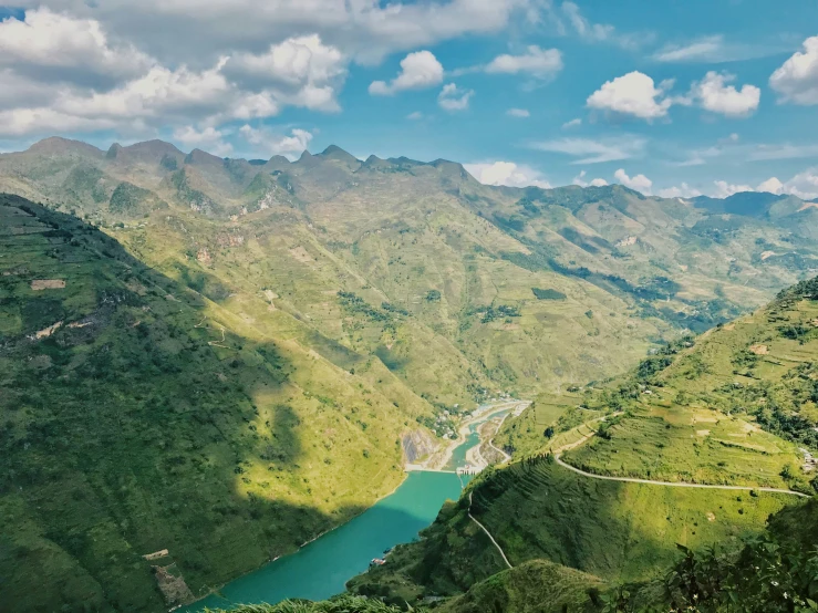 a valley is surrounded by green hills and trees