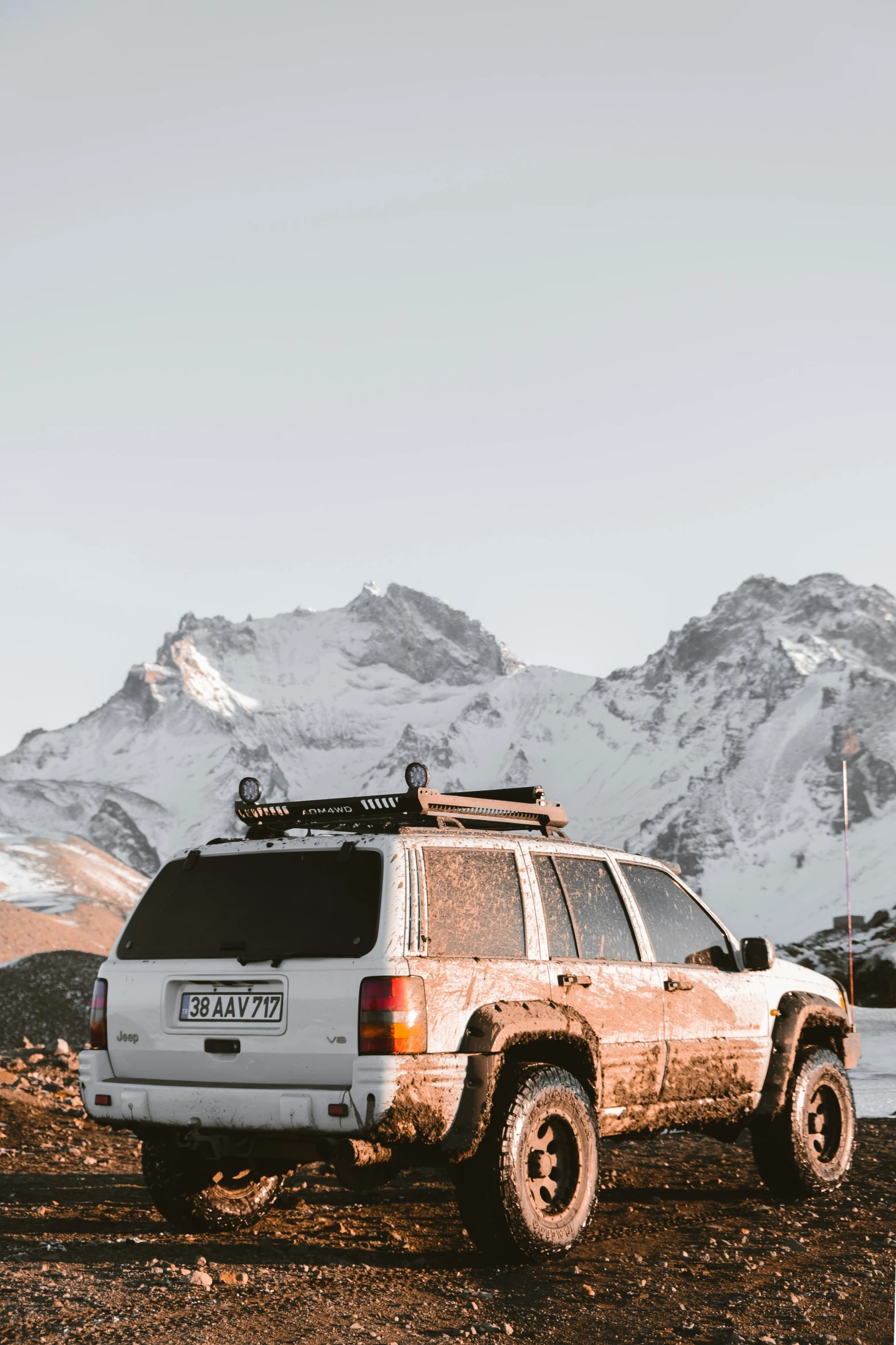 an old car sitting on the ground in front of a mountain range