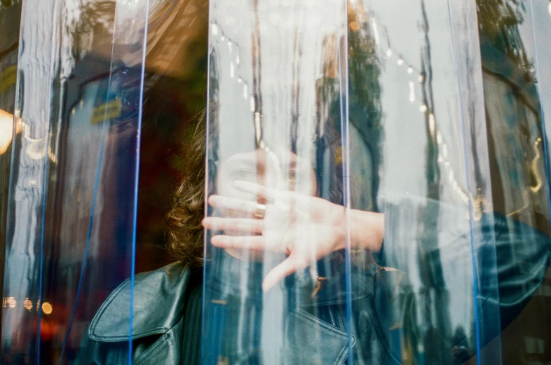 a person behind some curtains with their hand in the rain