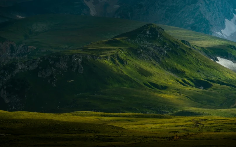 the mountains are green with grass in the foreground