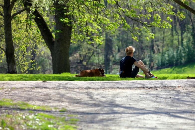 a young man sitting on the ground next to his dog
