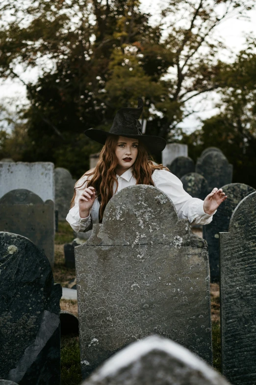 woman with a hat and feather dress in an old cemetery