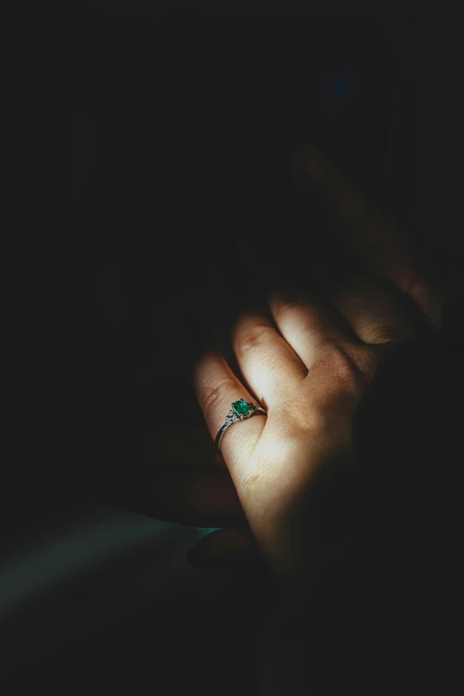 the hand is holding a ring with diamonds and emeralds