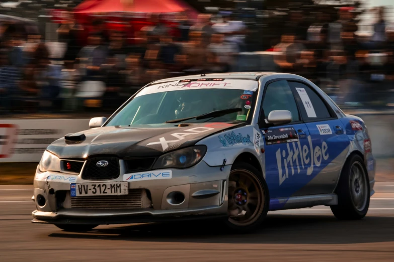 a race car turning down the track with spectators behind it