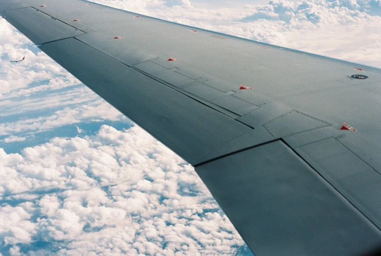 a airplane wing is flying above the clouds