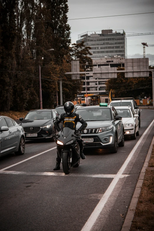 a person riding a motorcycle in front of some cars