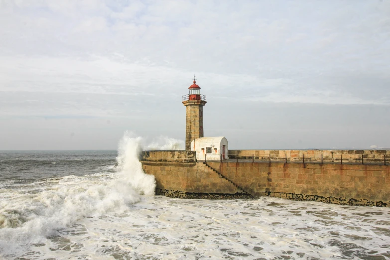 waves crashing into the cement wall at a lighthouse