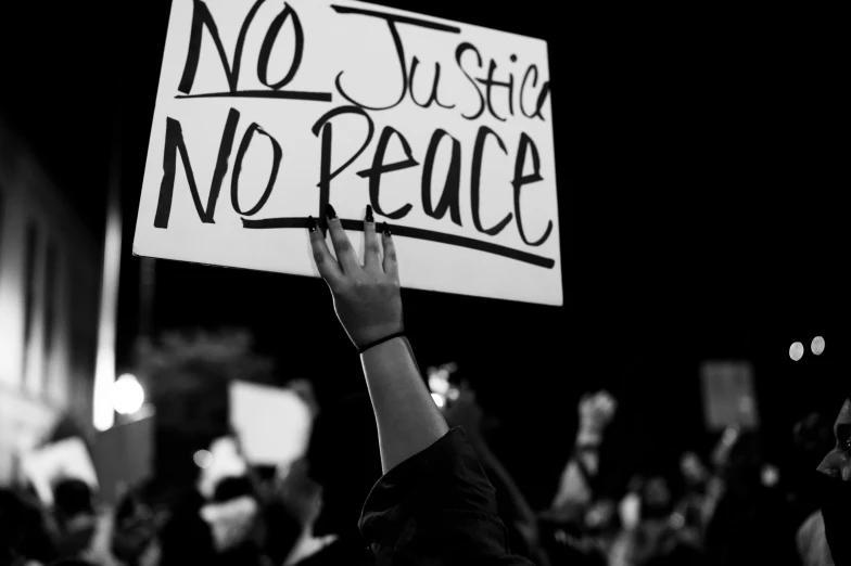 a person holding up a sign that says no justice no peace