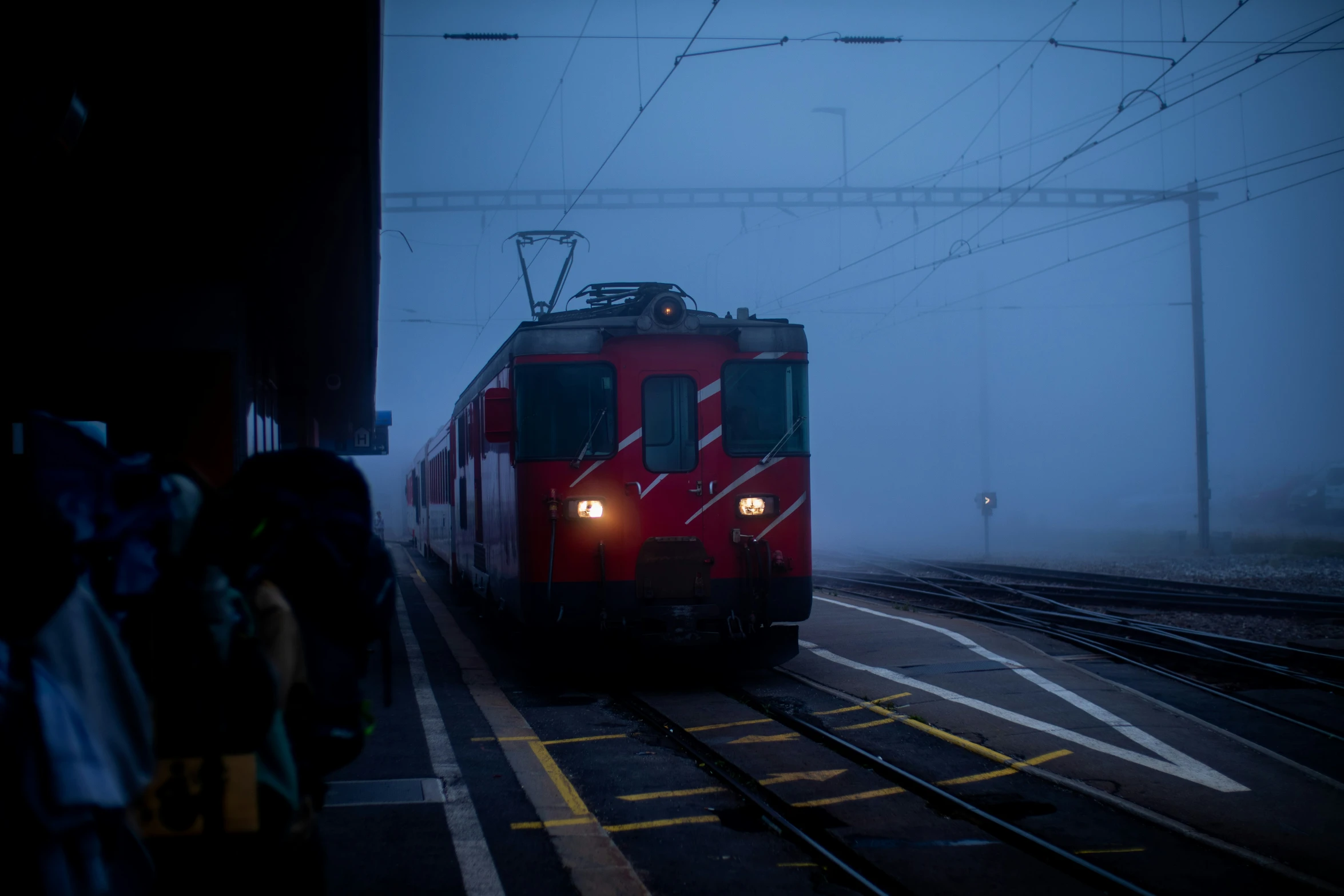 a red train going through foggy train station