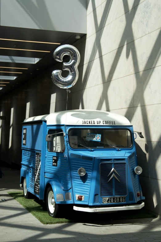 an old blue truck is parked next to a large number eight balloon